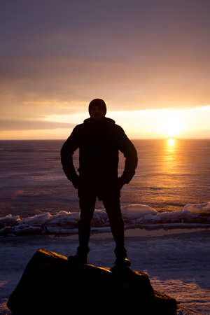 Man on a rock on the sea in the ice - silhouetteの写真素材