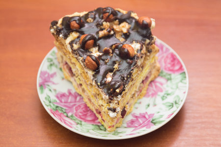 Piece of cake with hazelnuts and chocolate - in a saucer, background