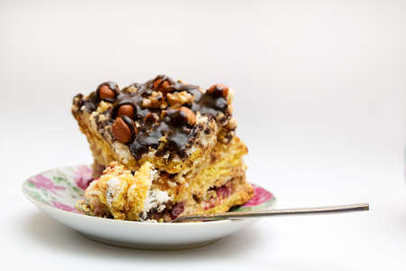 Piece of cake with hazelnuts and chocolate in a saucer, with a teaspoon - backgroundの写真素材