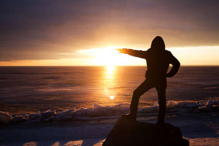 Man on a rock on the sea in the ice - silhouetteの写真素材