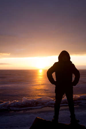 Man on a rock on the sea in the ice - silhouetteの写真素材
