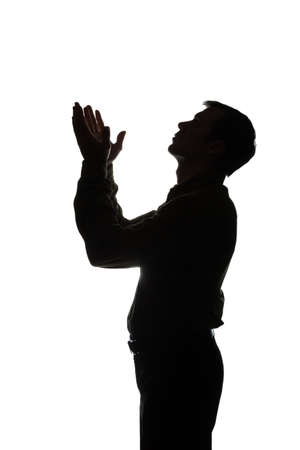 Young man looking up with hope and request - silhouette of a side viewの写真素材