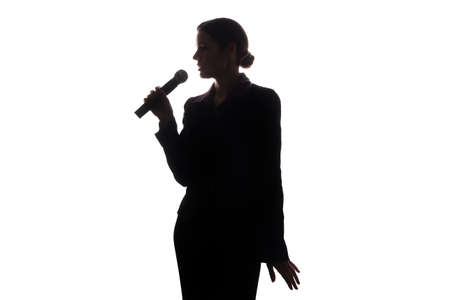 Young woman singing into the microphone, raising his hands - silhouetteの写真素材