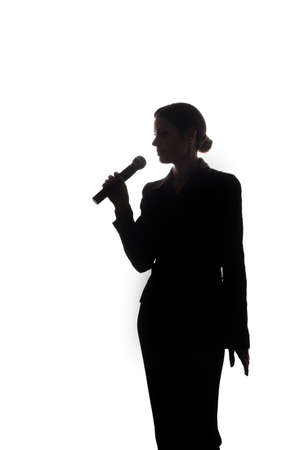 Young woman singing into the microphone, raising his hands - silhouetteの写真素材