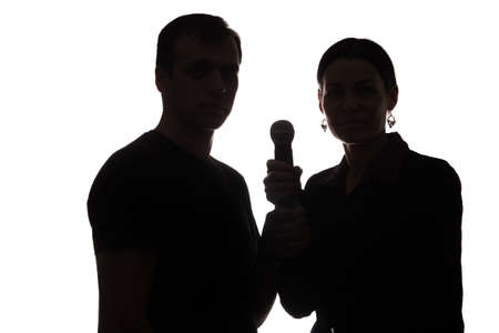 Young man and woman singing into the microphone, raising his hands - silhouetteの写真素材