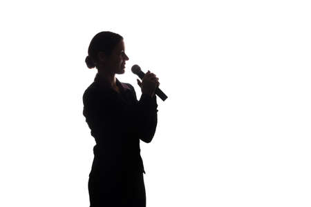 Young woman singing into the microphone, raising his hands - silhouetteの写真素材