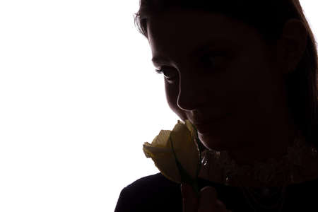 Young woman sniffs a flower - horizontal isolated silhouette of a side viewの写真素材