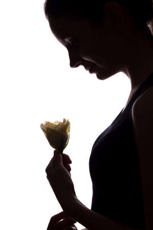 Young woman look ahead with flower - vertical, isolated silhouette of a side viewの写真素材