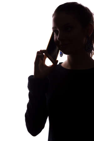 Young woman phone call - looks straight ahead, portrait isolate silhouette styleの写真素材