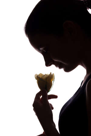 Young woman look ahead with flower - vertical, isolated silhouette of a side viewの写真素材