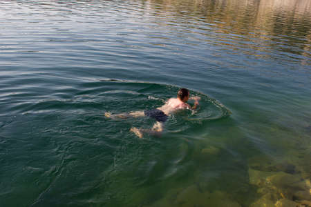 Male young swimmer on the water - background summer sunny seaの写真素材