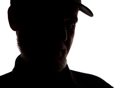 Portrait of a old man, in a peaked cap, with beard, side view - dark isolated silhouetteの写真素材