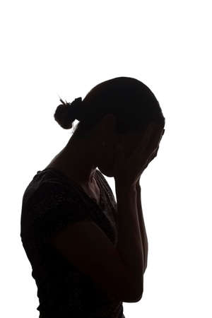 Silhouette of a young girl with problems, side view with hands on her head - isolated, nonameの写真素材