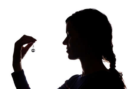 Young woman look ahead with flowing hair with an earring in his hand - isolated silhouetteの写真素材