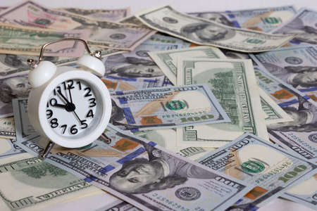 Clock on the background of a bundle of dollars on the table close-up, one hundred dollars washington, one thousand - texture, backgroundの写真素材