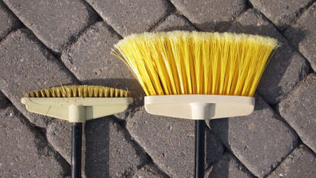 Very old and new brush for paving slabs on background of cleaned gray paving slabsの写真素材