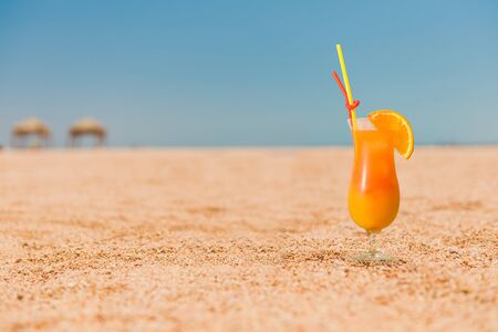ocktail with orange juice on sandy beachの写真素材
