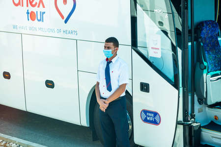 Egypt, Hurghada - 07/11/2020. tour guide in protective mask standing near buss entrance waiting for touristsのeditorial素材