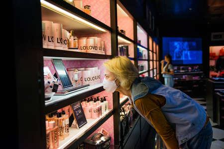 11.07.2020 - Kiev, Ukraine tourists woman in protective mask looking at shelf with famous brands in duty free shopのeditorial素材