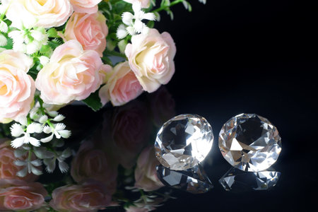 Couple of wonderful pure diamonds and bouquet of tea roses with reflection on black mirror background close up view. Jewelry diamonds sale, invitation, action, discount banner, poster templateの写真素材