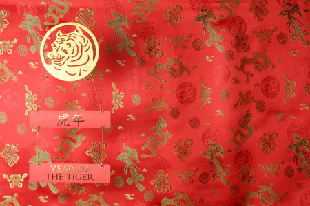 Chinese New Year of the Tiger 2022. Golden tiger symbol on red fabric with traditional chinese ornament birds and dragons. Translation: year of the tigerの写真素材