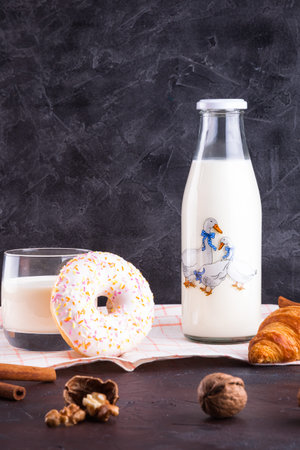 Bottle with milk, donut, walnuts, cinnamon sticks and croissantの写真素材