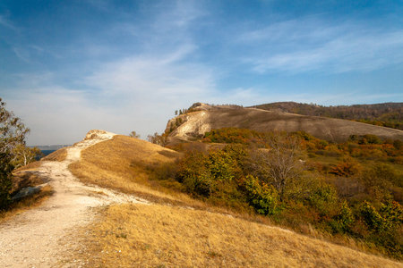 Magnificent Coastal View with Towering Cliffs, Lush Greenery, and the Deep Blue Sea Under a Partly...
