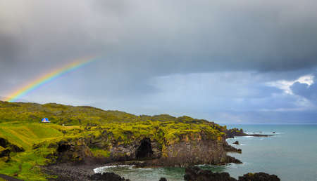 Icelandic coast with stormy skies and rainbowの写真素材