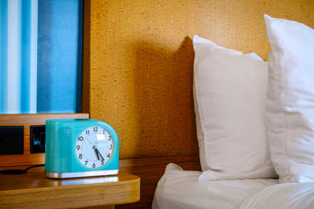 Bedside table with alarm clock at a hotelの写真素材