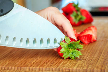 Closeup image of strawberries being prepared for cooking on a cutting boardの写真素材
