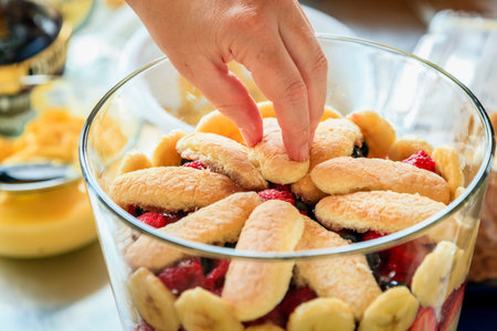 Closeup image of trifle being prepared in a glass bowl