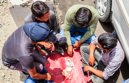 Ladakh, India - July 10, 2016: Taxi drivers play cards wile waiting for their passengers
