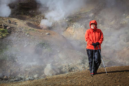 Hiker is standing near boiling springs in Reykjadalur Valley in South Icelandの写真素材