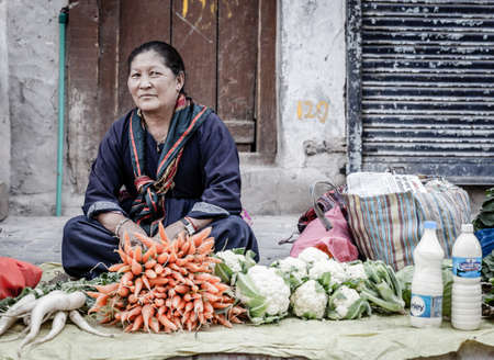 Leh, Ladakh, India, July 12, 2016: local woman is selling produce and milk on a sidewalk market in Leh, Ladakh district of Kashmir, Indiaのeditorial素材