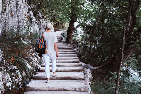 Woman is walking on a trail along a creek in Plitvice Lakes National Park in Croatiaの写真素材