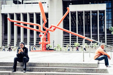 Cape Town, South Africa, February 9, 2018: People resting on steps in front of the Knot - modern art...
