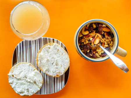 Top-down view of breakfast set with muesli, bagel and grapefruit juice