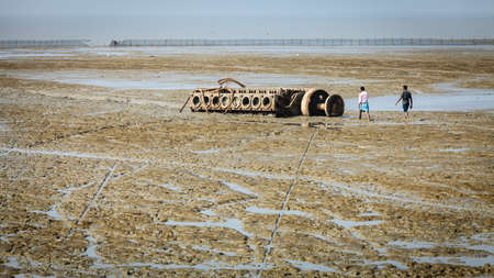 Chittagong, Bangladesh, December 23, 2017: Men are walking towards a large ship engine block sunk in the mud at one of ship-breaking yards in Chittagong, Bangladeshのeditorial素材