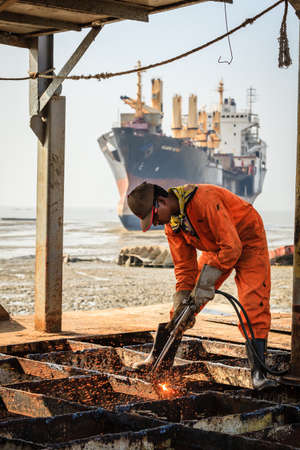 Chittagong, Bangladesh, December 23, 2017: A worker is cutting through metal deck structure of a ship at a ship-breaking yard in Chittagong, Bangladeshのeditorial素材