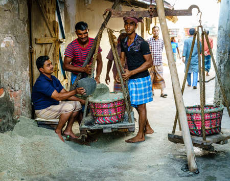 Chittagong, Bangladesh, December 22, 2017: Men weighing baskets with salt at a factory in Chittagong, Bangladeshのeditorial素材