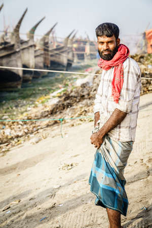 Chittagong, Bangladesh, December 23, 2017: Portrait of a middle-aged fisherman with traditional fishing boats in the backgroundのeditorial素材