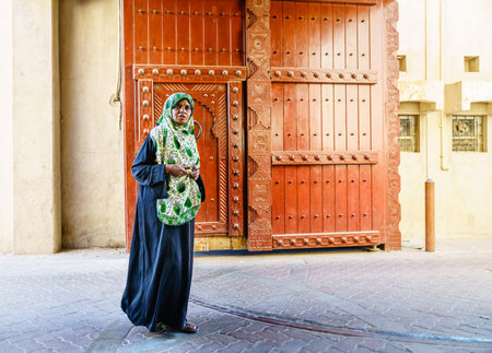 Nizwa, Oman, December 2, 2016: Middle-aged local woman is walking  through the town gates at Friday Market in Nizwa, Omanのeditorial素材