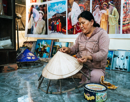 Hue, Vietnam, November 18, 2022: A woman is making traditional vietnamese conical hats at a shop in Hue, Vietnamのeditorial素材