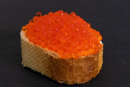 Red caviar with white bread on the grey stone background