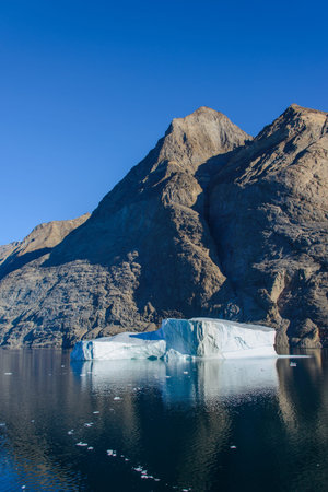 Greenland landscape with beautiful coloured rocks and iceberg.