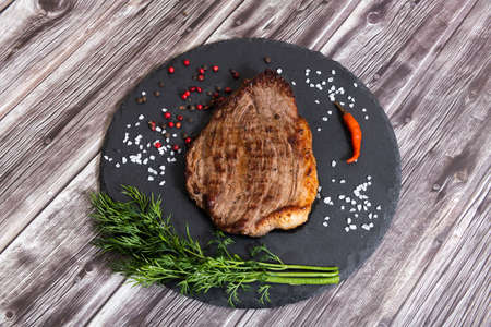 Grilled beef steak ribeye with salt and pepper on dark wooden background top viewの写真素材