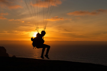 Paraglider flying over thesea shore at sunset. Paragliding sport concept.の写真素材