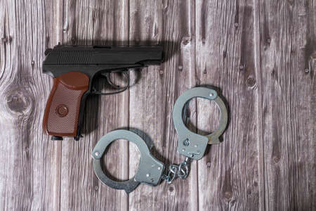 Handcuffs and Makarov gun on dark wooden table. Copy space.の写真素材