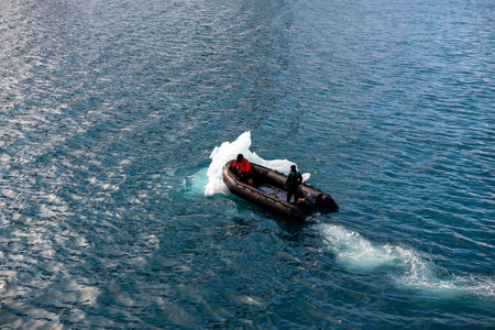 Inflatable boat with one person in Arctic waters, Svalbard. Pushing ice.