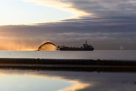 Large tube on loader. Tractor. Construction Marine offshore works. Dam building, crane, barge, dredger.の写真素材